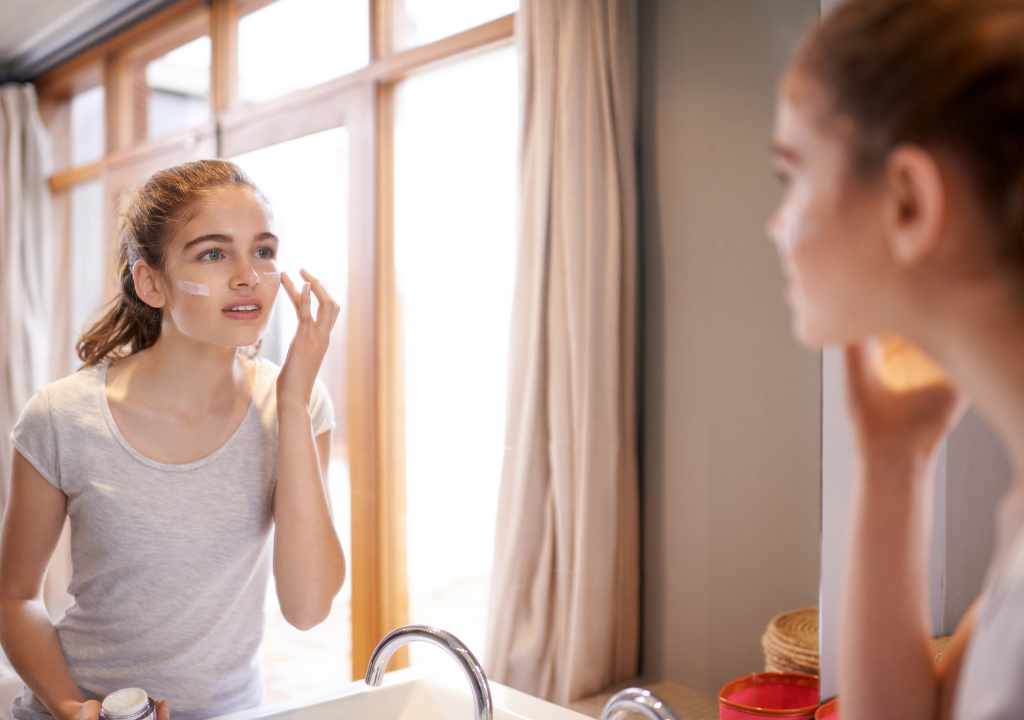 Woman applying skincare looking into a mirror