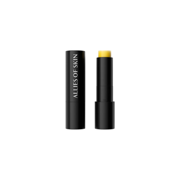 A yellow cosmetic stick, shown uncapped with its black cap removed, next to its black cap. The brand name 'ALLIES OF SKIN' is printed vertically in white on the left black cap.