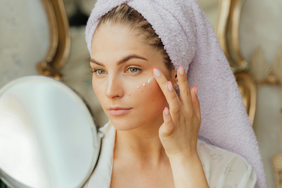 Woman looking into a mirror and applying cream onto her face