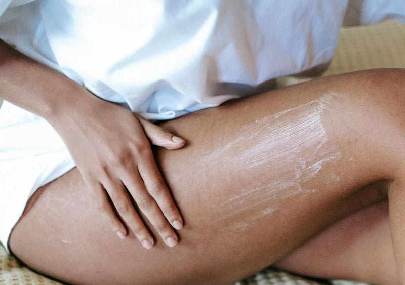 Lady applying body lotion to her legs