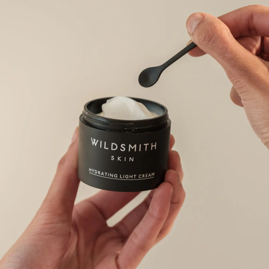 Person holding a jar of Wildsmith Skin cream with a spoonful being lifted.