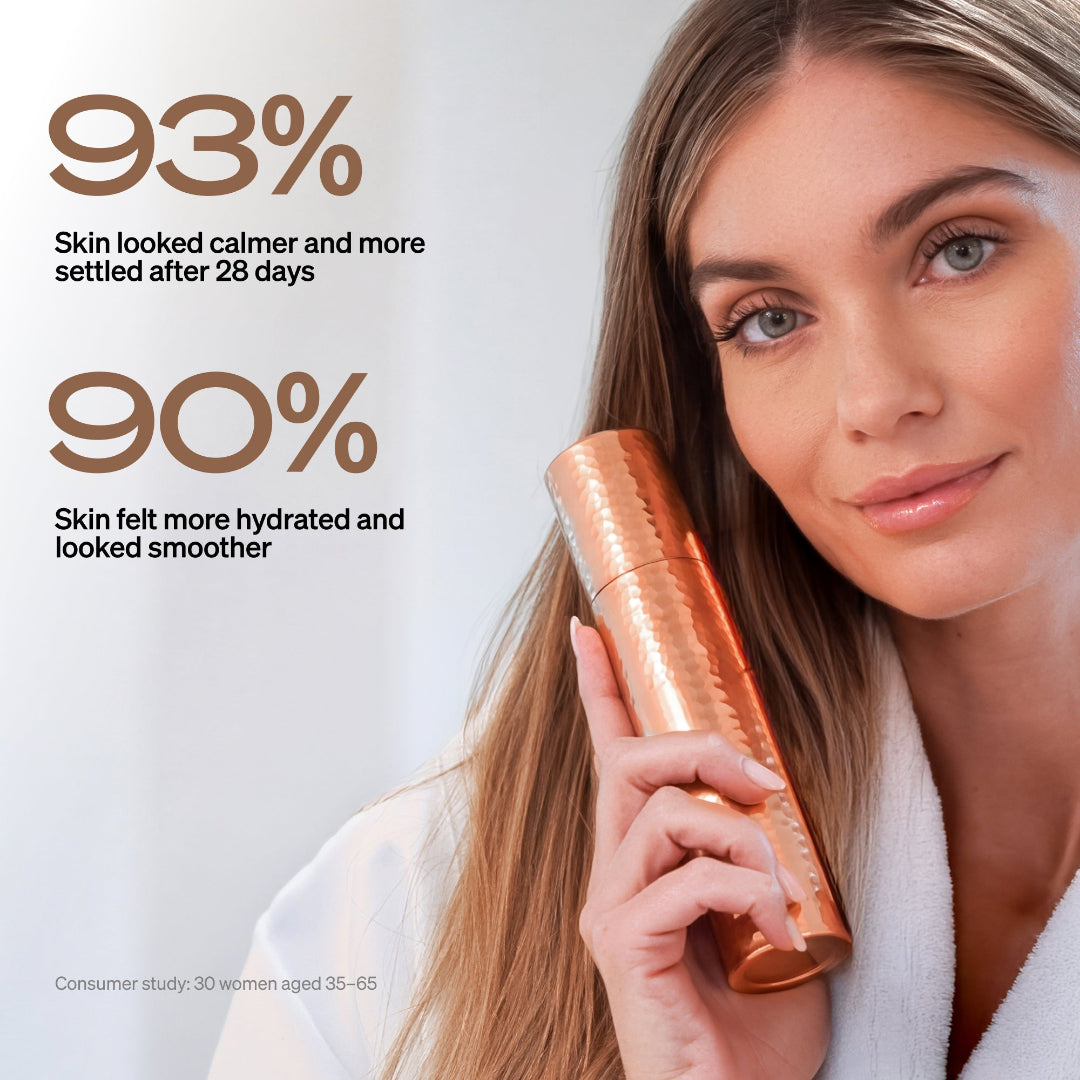 A woman in a white robe holds a metallic copper-colored cosmetic bottle against a soft light background, with promotional text reading '93% Skin looked calmer and more settled after 28 days' and '90% Skin felt more hydrated and looked smoother.'.