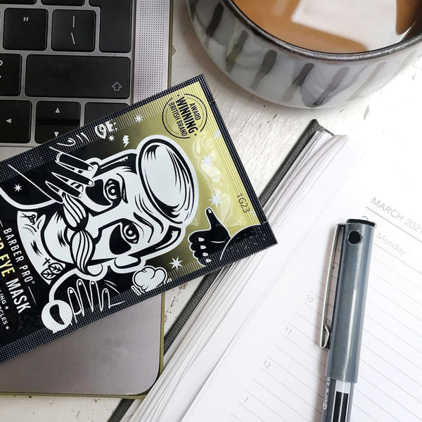 Barber eye mask packaging on a desk with a laptop, pen, and coffee cup.