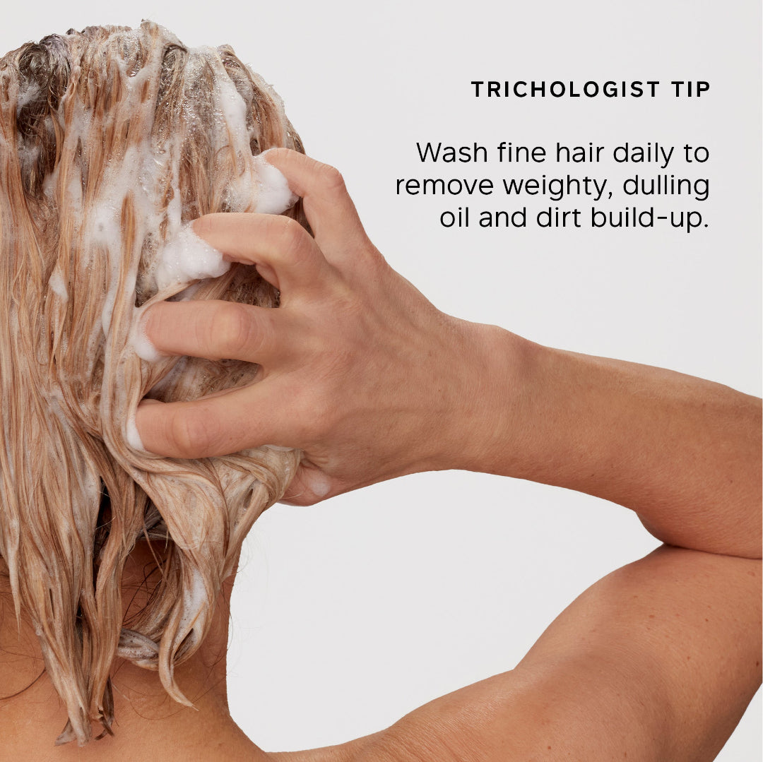 A person washing fine hair with shampoo foam, shown from the back against a light gray background, with the text 'TRICHOLOGIST TIP' and a tip about washing fine hair daily.