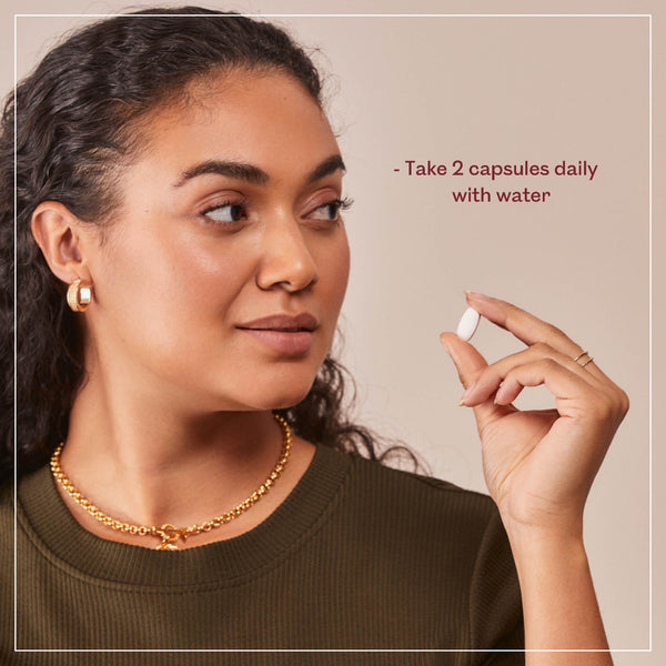 Woman holding a supplement capsule with text on a beige background