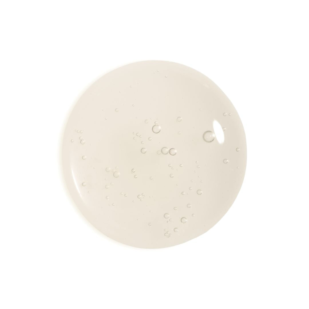 A circular swatch of translucent, slightly glossy cream-colored gel or liquid with small air bubbles, centered on a solid white background.