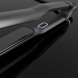 A sleek black and dark gray hair straightener shown at an angle on a glossy black reflective surface.