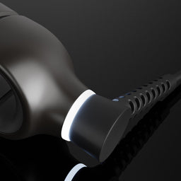 Close-up of a matte black hair straightener with a glowing white indicator light, set against a dark reflective background.