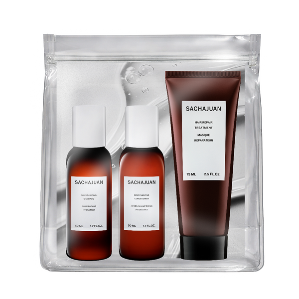 Sachajuan hair care set in a clear zippered pouch, featuring a brown hair retainer treatment tube and two brown bottles with white caps, shown on a white background.