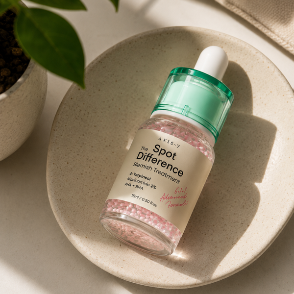Skincare dropper bottle labeled 'Spot Difference' on a beige plate with a plant in the background