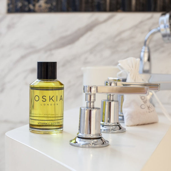 OSKIA Vitamin E Bath Oil bottle on a bathroom countertop