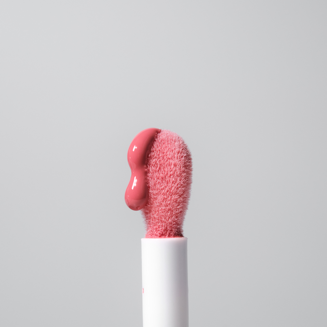 Pink lip balm on a white stick against a light gray background
