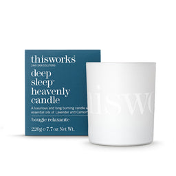 A white glass candle jar with a subtle embossed logo next to its dark teal-blue packaging box. The box features white text reading 'thisworks deep sleep heavenly candle'.