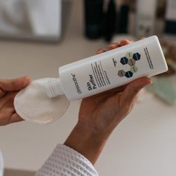 Clinisoothe+ Skin Purifier Bottle being applied to a cotton pad