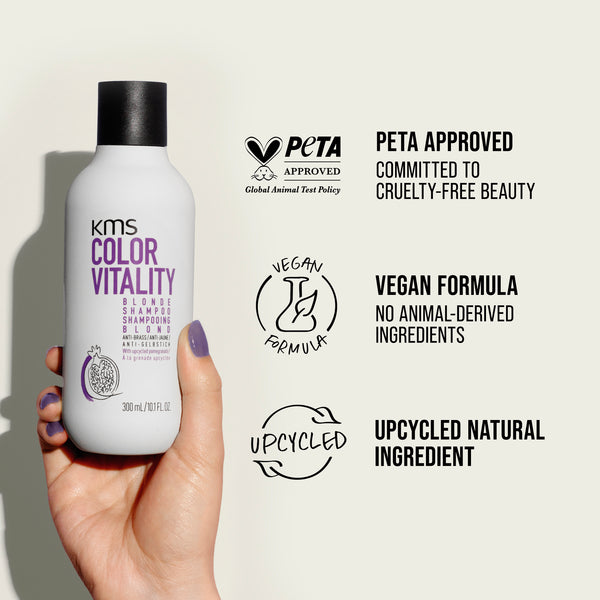 KMS Color Vitality shampoo bottle held by a hand with PETA approval and vegan formula labels on a light background.