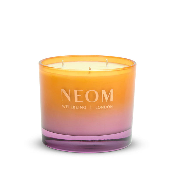 Neom candle with gradient orange to pink design on a white background