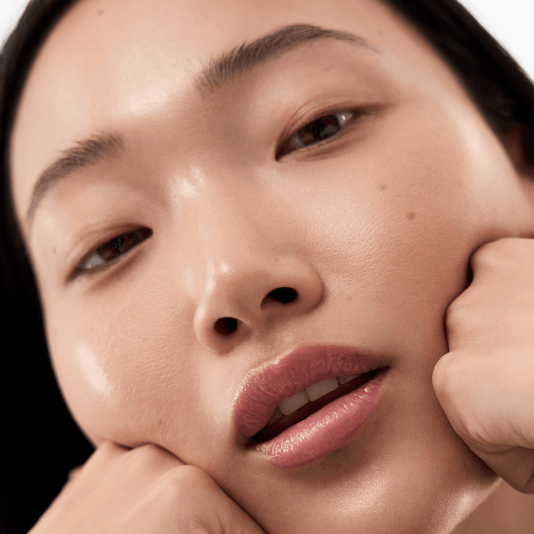 Close-up of a person with their hand near their face against a white background