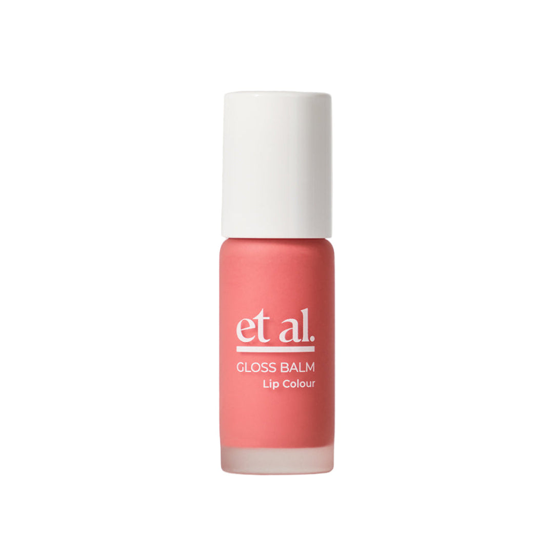 Lip balm with coral color and white cap on a light gray background