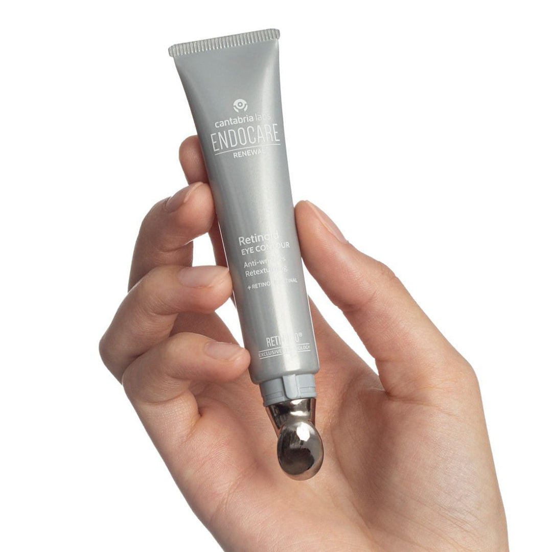 Hand holding a silver tube of Caudalie eye cream against a white background