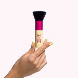 Coco & Eve Sunny Honey Deluxe Vegan Kabuki Brush being held in a hand