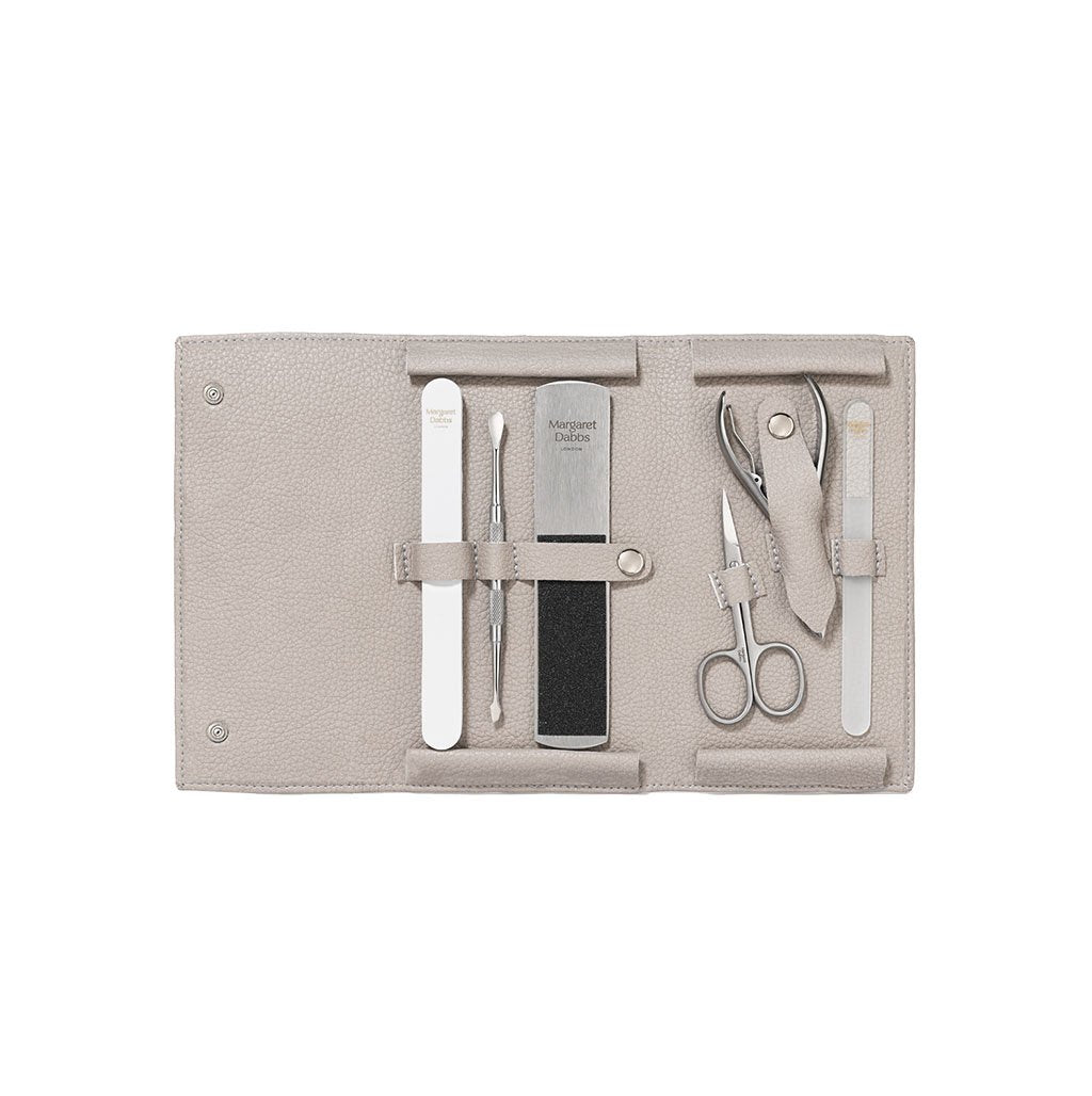 Manicure set with tools on a beige fabric case against a white background