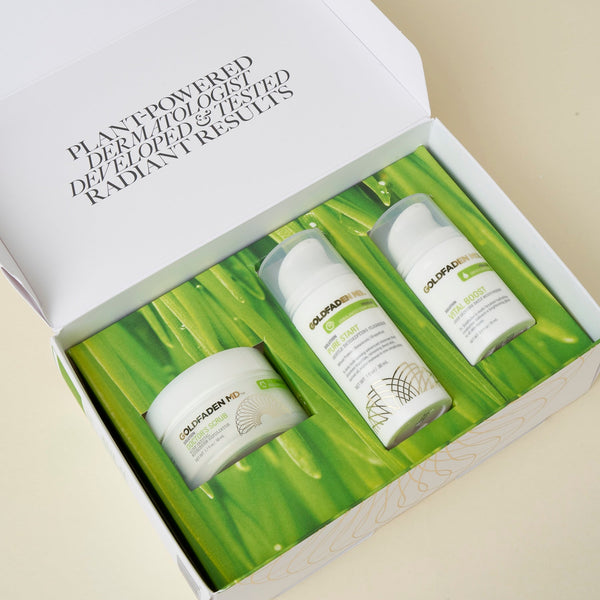 An open white gift box containing three white skincare bottles and a white jar, arranged on a green leaf-patterned insert. The inside lid reads 'PLANT-Powered DERMATOLOGICAL DEPIGMENTATION AND FLAWLESS RESCUE.