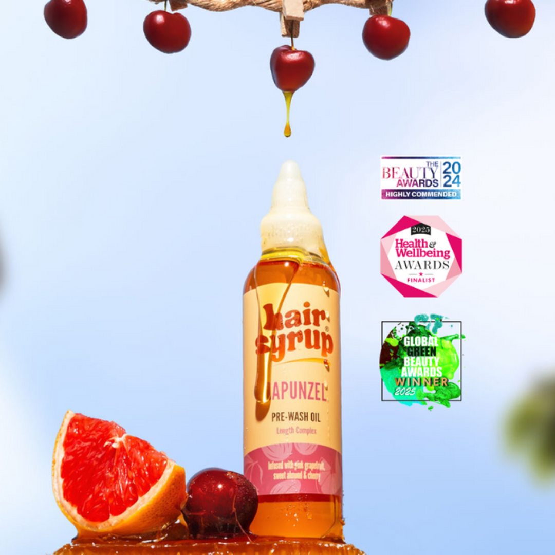 Hair syrup bottle with cherry and grapefruit on a blue background, featuring awards logos.