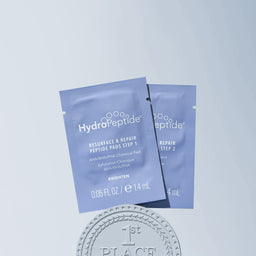 Two HydroPeptide skincare product packets on a light blue background