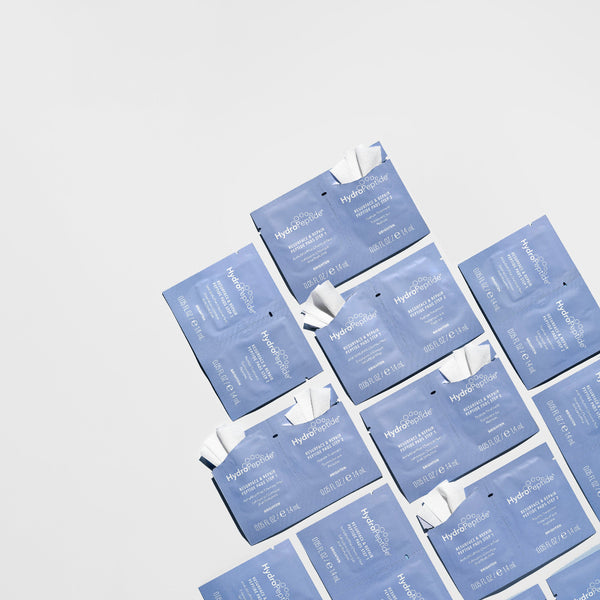 Multiple blue skincare mask packets arranged on a light gray background