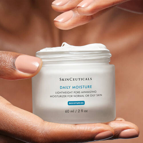 a hand dipping their fingers into a tub of SkinCeuticals Daily Moisture