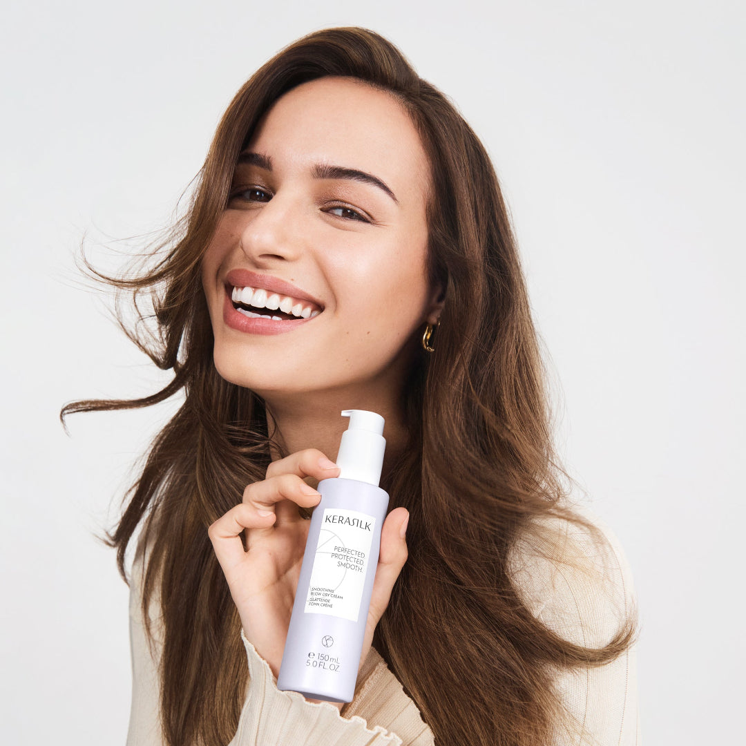 Woman holding a skincare product with a plain background