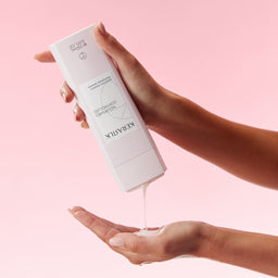 Hand holding a white skincare product with 'KEFRAUK' branding against a pink background