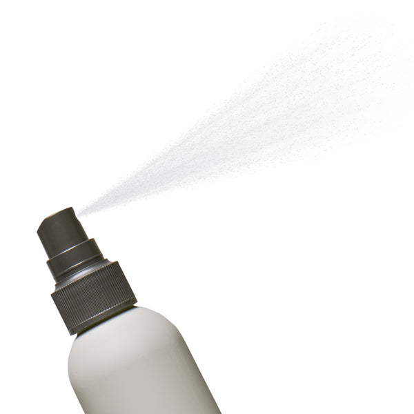 Spray bottle with a stream of liquid on a white background