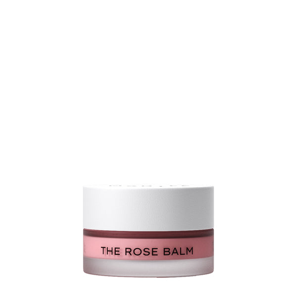 A small cosmetic jar labeled 'THE ROSE BALM' with a white lid and a dusty rose-pink band around the lower middle, shown on a plain white background.