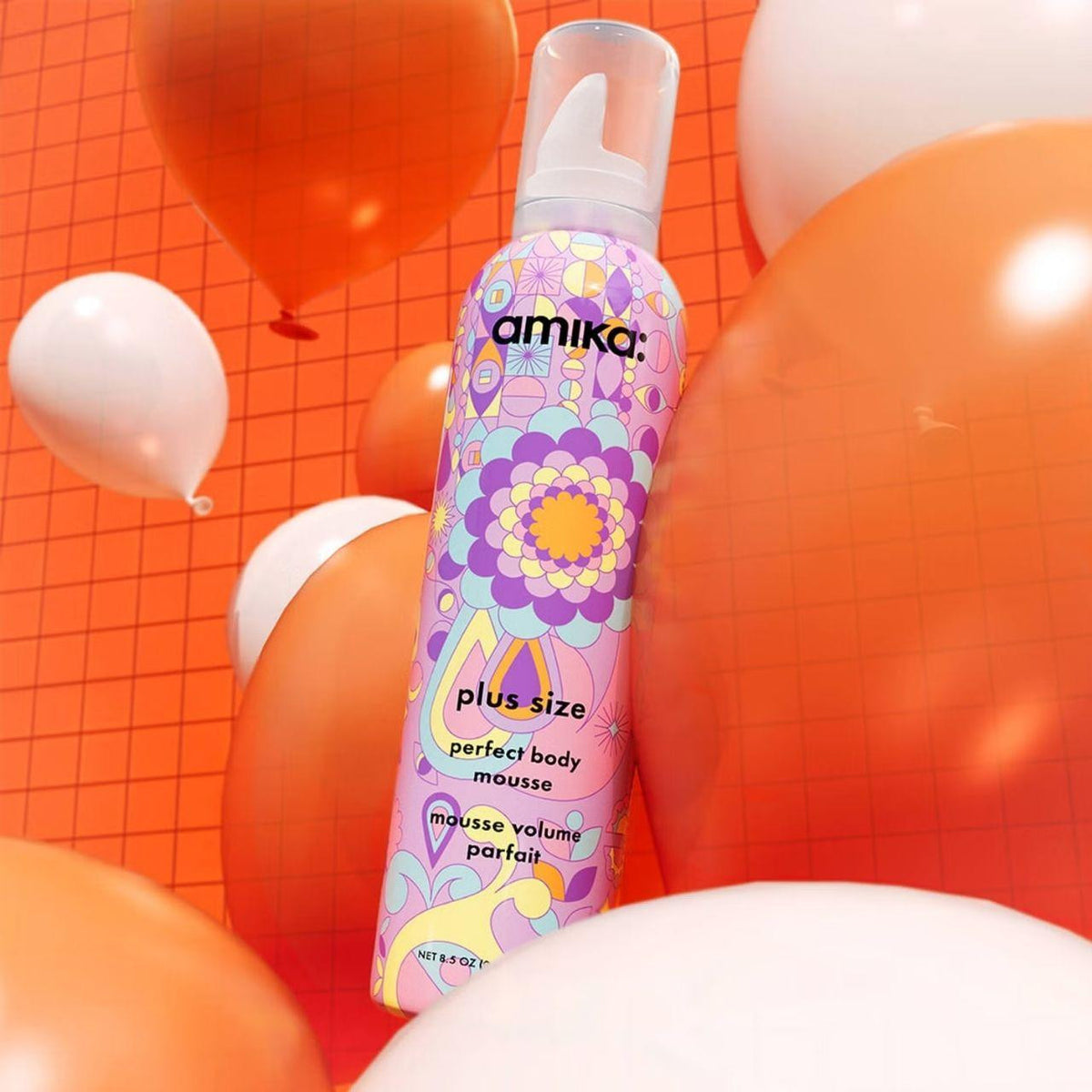 Amika product with colorful design against an orange grid background with balloons
