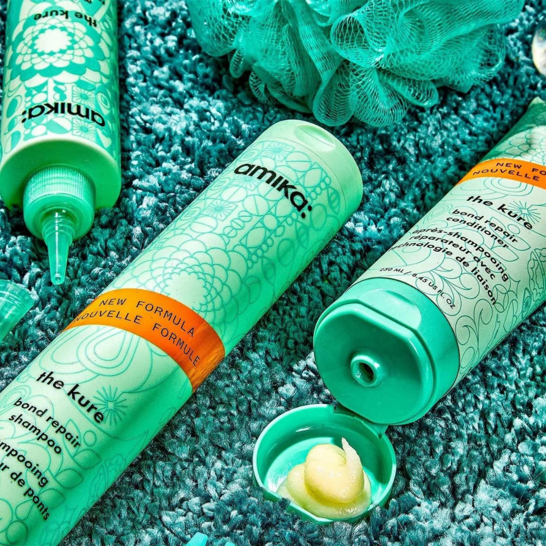 Amika hair care products on a textured blue surface
