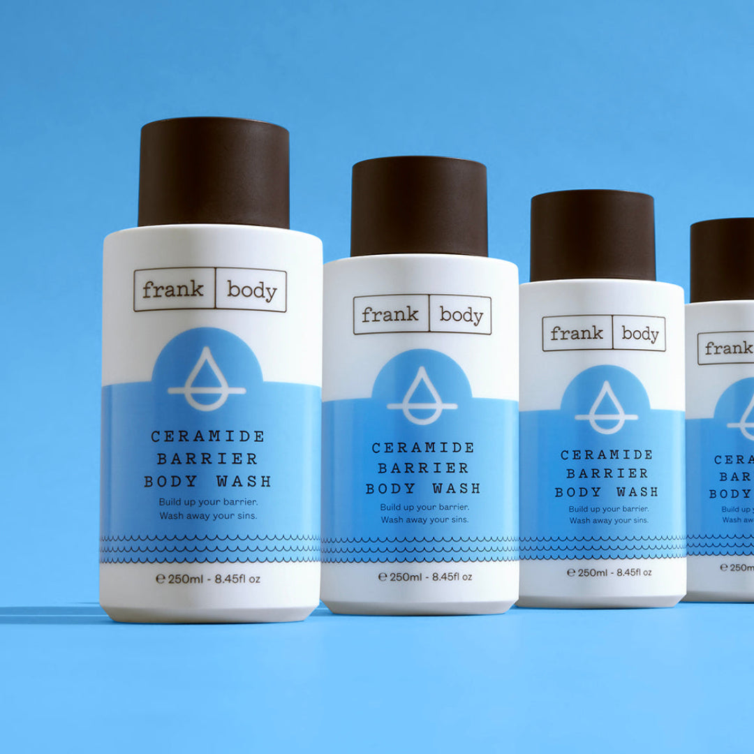 Four bottles of Frank Body Ceramide Barrier Body Wash on a blue background