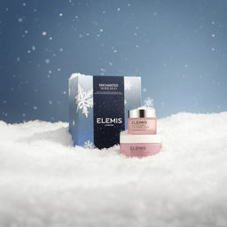 Elemis skincare products in the snow with a blue sky background