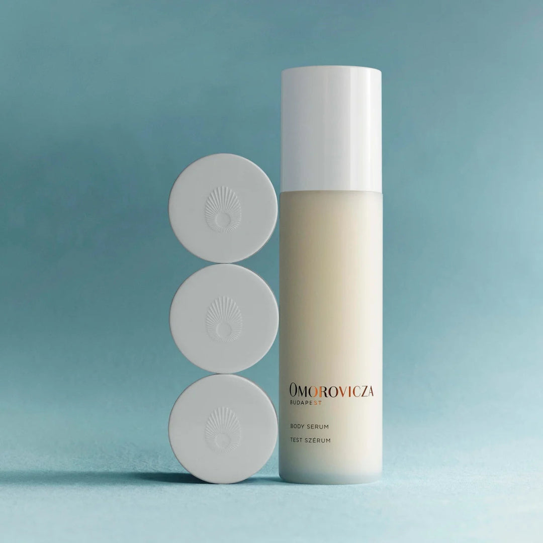 Omorovicza body serum bottle with three circular applicators on a light blue background