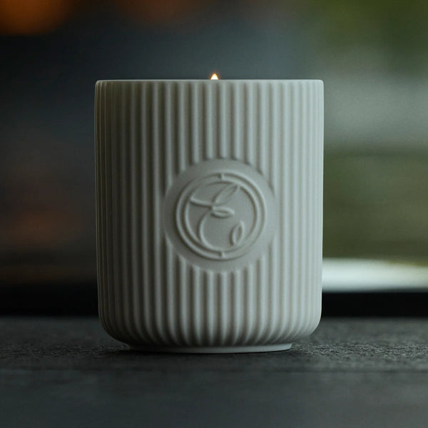 White textured candle with a logo on a dark surface