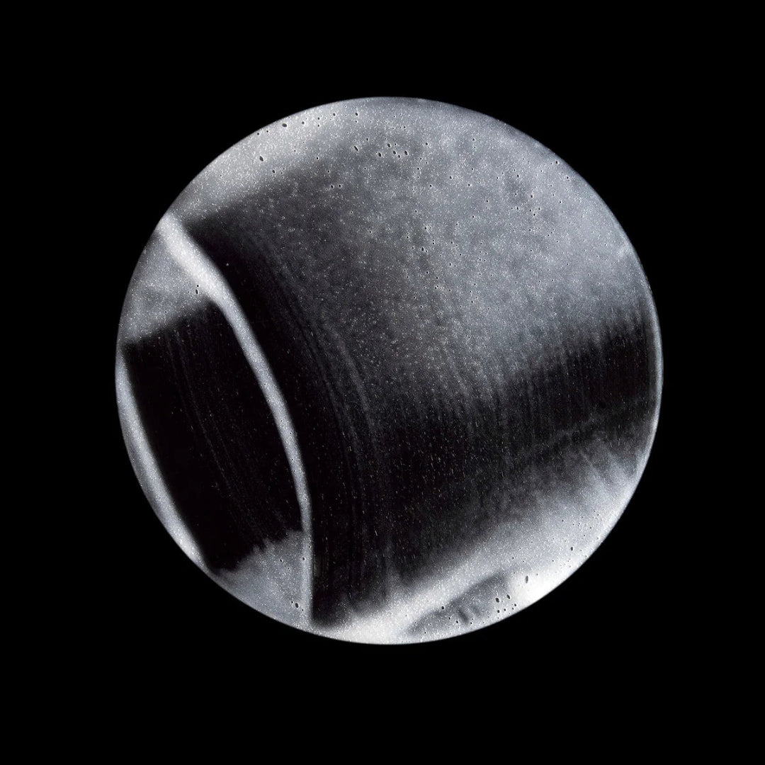 Black and white circular object with reflective surface on a black background