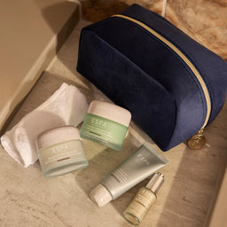Espa skincare products on a marble surface with a navy blue pouch.