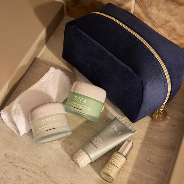 Espa skincare products on a marble surface with a navy blue pouch.