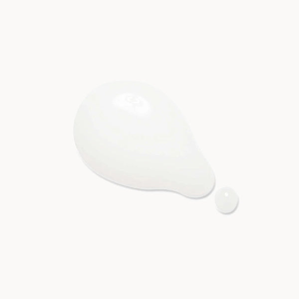 A glossy white teardrop-shaped droplet of cream or serum with a small separate droplet beside it, centered on a very light off-white background.