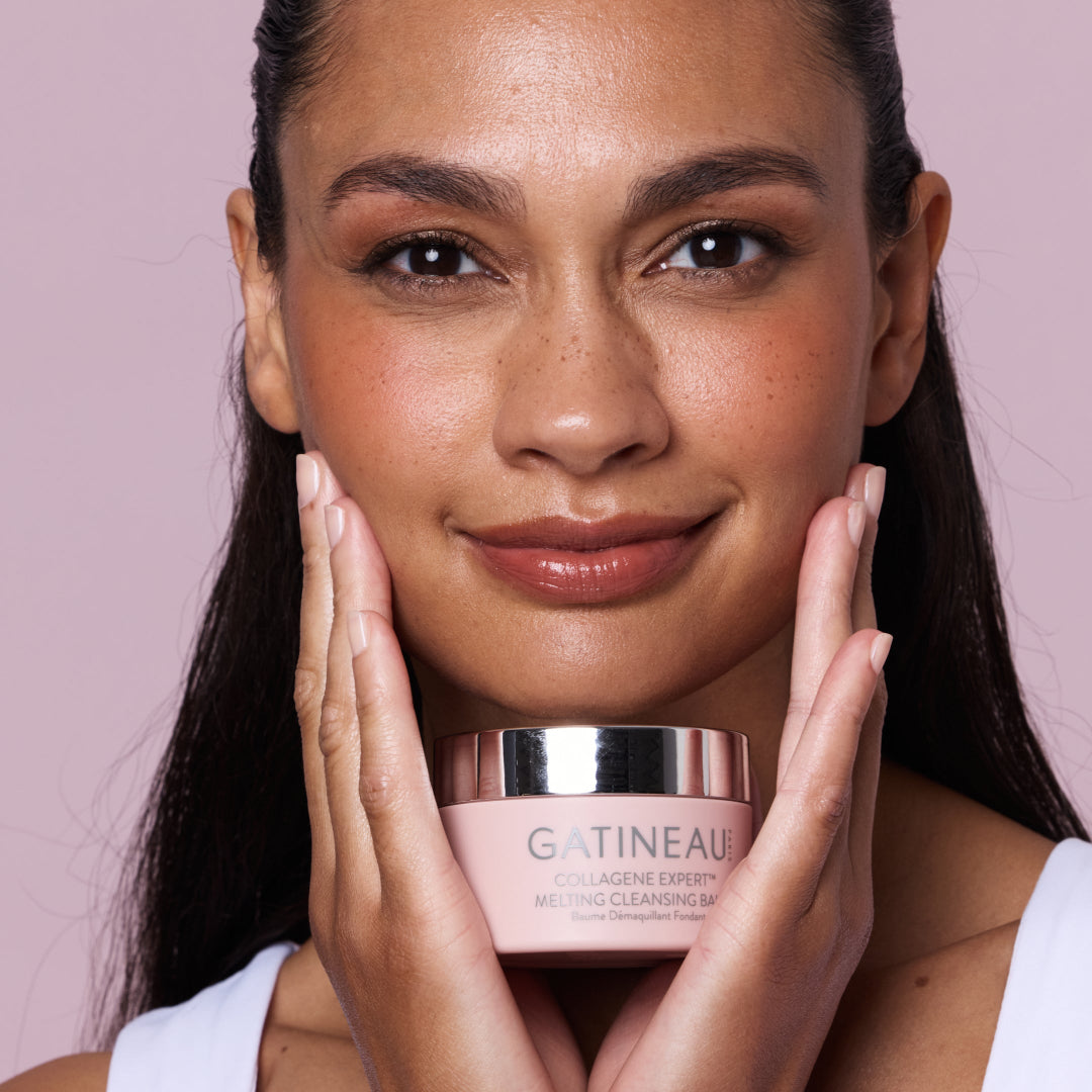 Woman holding a Gatineau skincare product against a pink background
