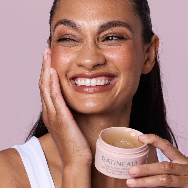 Woman holding a jar of Gatineau skincare product against a pink background
