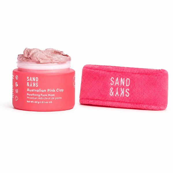 A jar of Sand & Sky Australian Pink Clay purifying face mask next to its matching pink pouch, both on a clean white background.