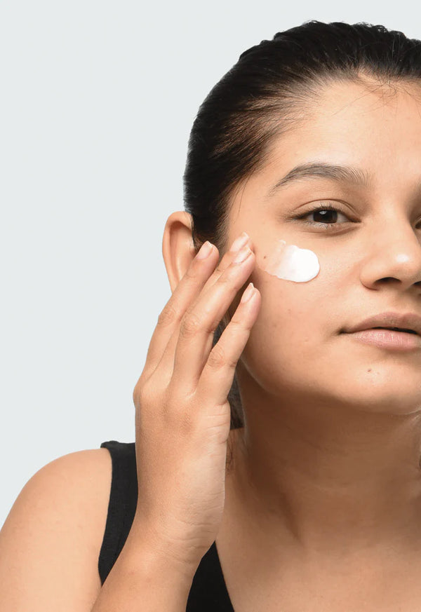 a women applying Minimalist Sepicalm 03% Moisturizer to her cheek