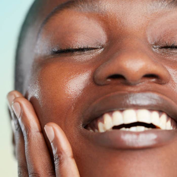 Close-up of a woman with her eyes closed, touching her face with her hand.