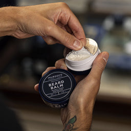 the metallic lid being pealed off the Murdock London Beard Balm tub